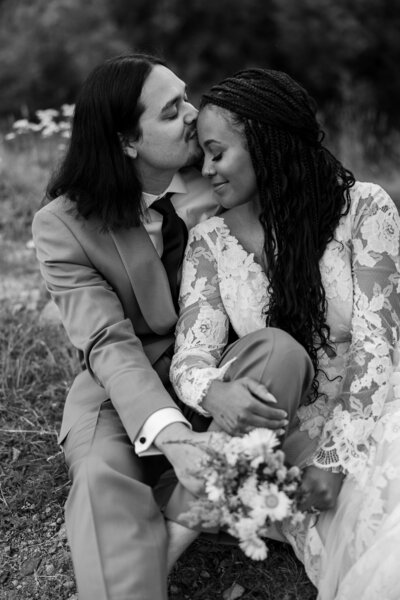 Black and white photo of a groom kissing his bride at Crystal Lake on Red Mountain Pass in Ouray, CO, capturing an intimate and dramatic moment