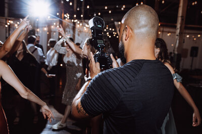 Joe Catoe carries his camera with him on the dance floor at a wedding reception