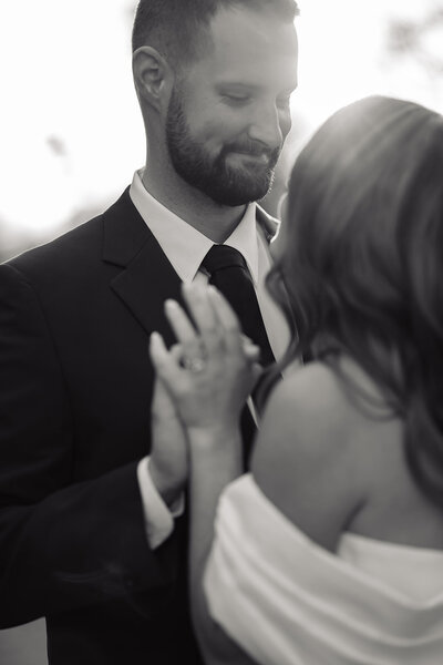 Bride and groom grabbing hands as they sway back and forth outside in black and white