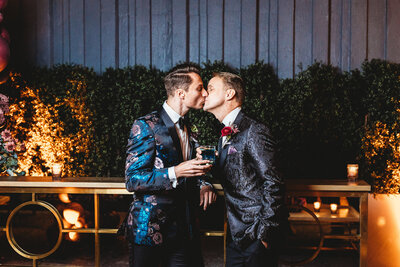 LGBTQ+ couple kisses during cocktail hour at hotel wedding.