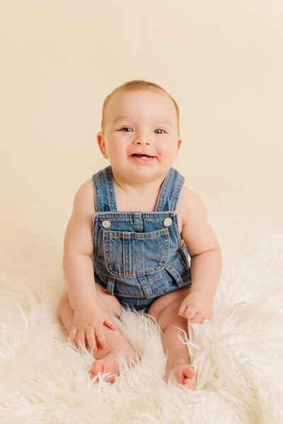 6-month portrait session of a child in blue overalls, taken in a studio in Richmond.