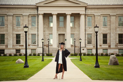 Female college graduate in her gown in front of the Old Capitol Building at the University of Iowa. 