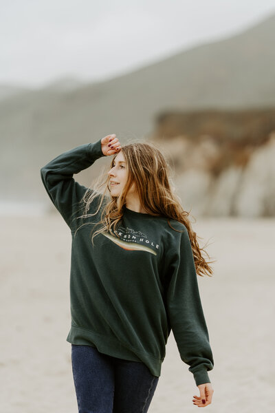 Photo of Hannah with her hand on her head, standing on the beach