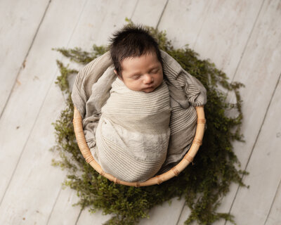 newborn baby boy wrapped in tan for studio portrait