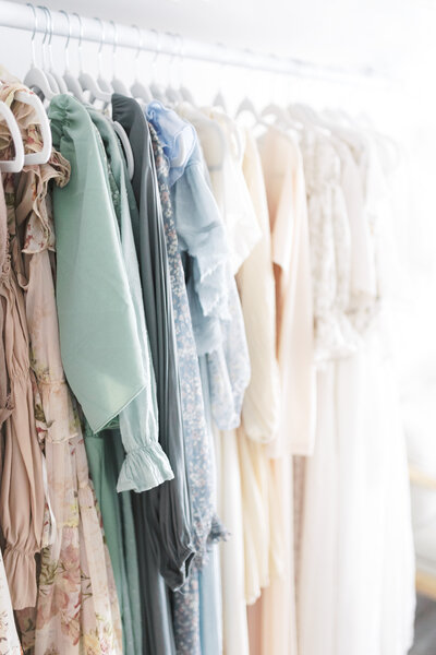 A collection of dresses hanging on a clothing rack available for chelsea nichole photography's grand forks clients to use during their photography session. 