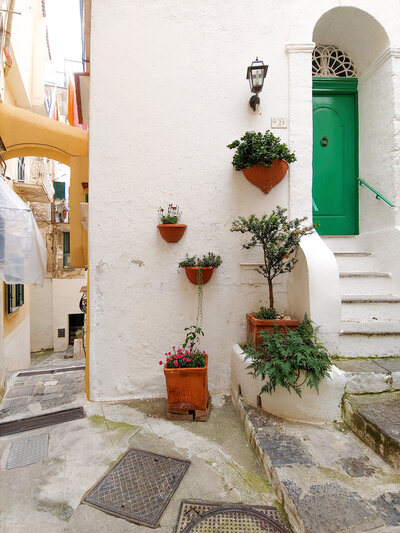 A beautiful alley leading up to a bright green door in Atrani, Italy on the Amalfi Coast.