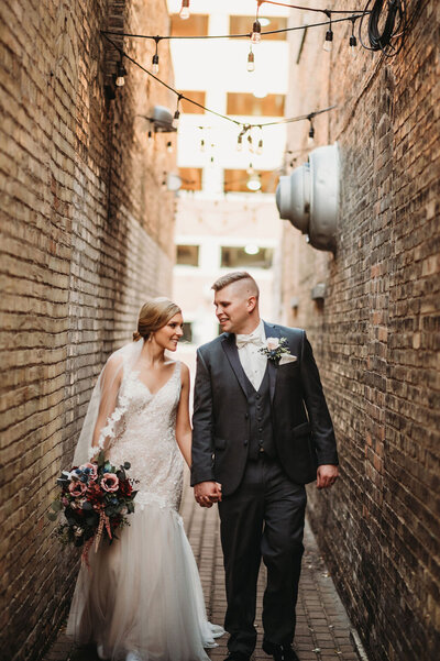 illinois wedding with bride and groom holding hands and walking down alley