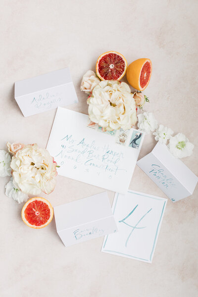 Flatlay photo with blue watercolor calligraphy envelopes, table number and escort cards