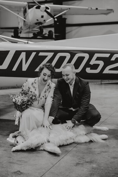 Zach and Zoe love on their doggy ring-bearer in front of their Alaskan airplane
