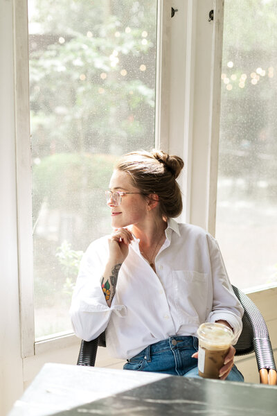 Blonde female interior designer stages a bed during brand photography session