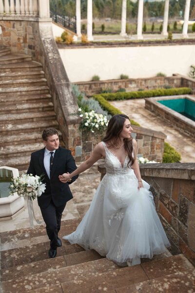 A bride and groom walk up some stone stairs at the Chateau De Lis in Oregon City, OR