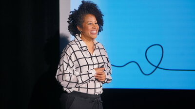 Woman on stage in front of presentation slides.