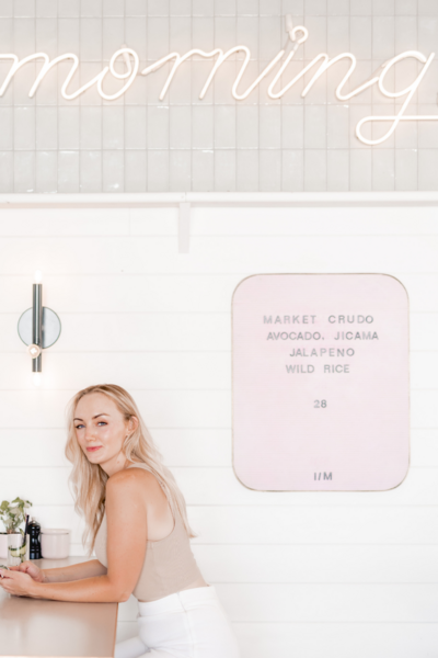 Hollie looking at the camera while sitting in a pink walled restaurant