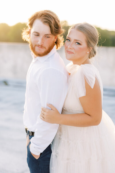 Black and white photo of groom with his back to the camera holding bride's hand while bride smiles at the camera before their sparkler exit