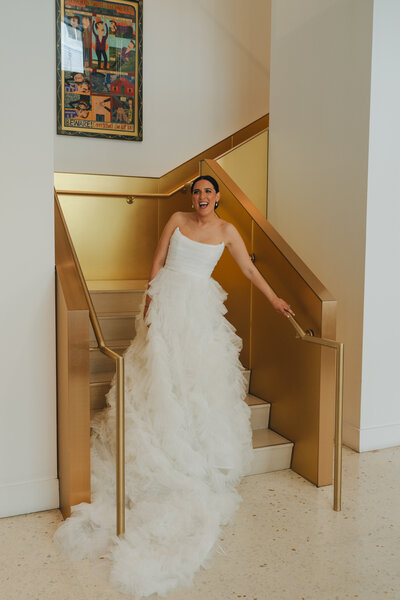An editorial style bride smiling leaning up against a gold staircase at a hotel in Chicago, Illinois. 