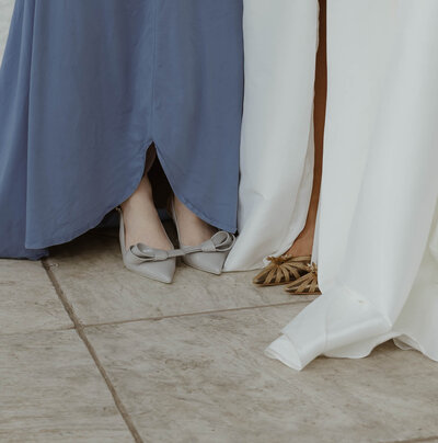 A close-up photograph of a bride and her maid-of-honor's trendy gold and blue shoes. Taken on the steps of the Buffalo Museum, downtown buffalo, NY. Photo by Dash and Boheme Photography. 