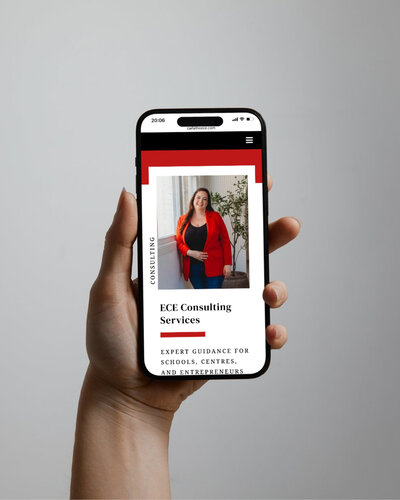 Hand holding a smartphone displaying Carla Ward’s ECE Consulting Services website, featuring a red and white modern design.