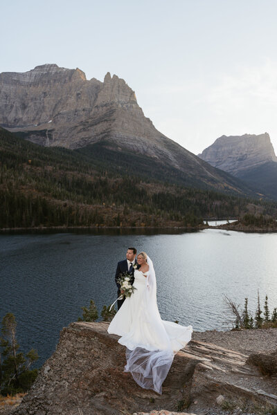 Montana Elopement Photographer. Couple holds hands while hiking in Glacier National Park with "just married" signs on their back packs.