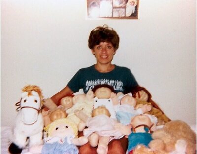 80s mom sits beneath a pile of Cabbage Patch Kids