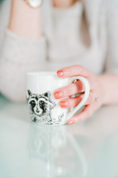 Becca Mai with a raccoon coffee mug