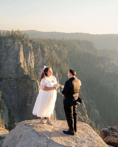 Bride and groom reading vows during elopement ceremony during sunset at Yosemite National Park Taft Point.
