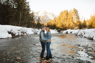 Engagement session in the Cascade Mountains. Riverfront with mountains visible in the distance.