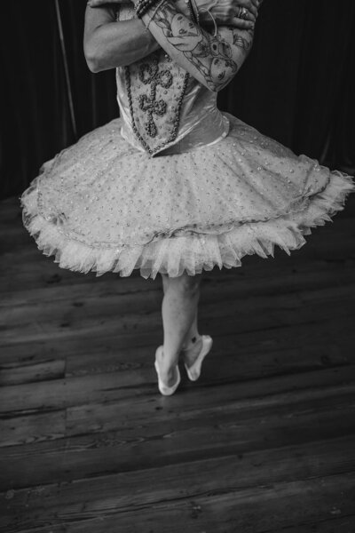 A tattooed ballet dancer standing on their toes 
