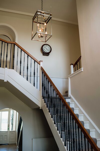 The entrance hall and staircase of Kinclune House wedding venue is photographed as light fills the space.