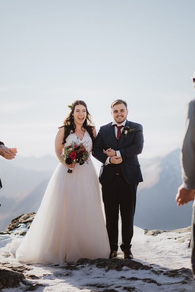 bride and groom laughing on snowy mountain