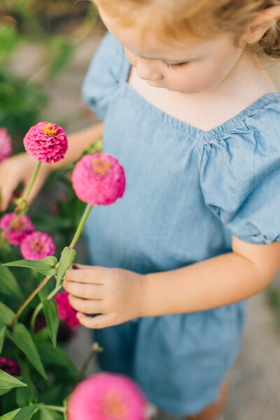 photo of a little girl looking at flowers