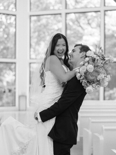 bride and groom in black and white at Osage House in Cave Springs, NWA Arkansas. Groom lifts bride and bride is laughing at camera