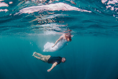 couple swimming in wedding clothes