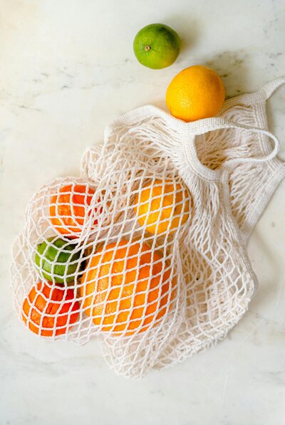 Netted bag full of citrus fruit laying on a white counter