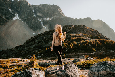woman standing on rocks with mountains in background
