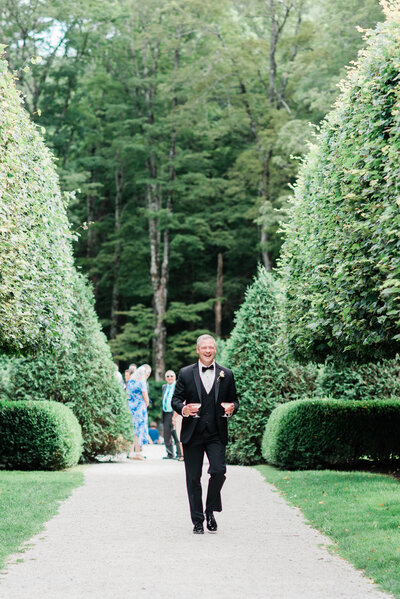Father of the bride walks down the aisle smiling wide 