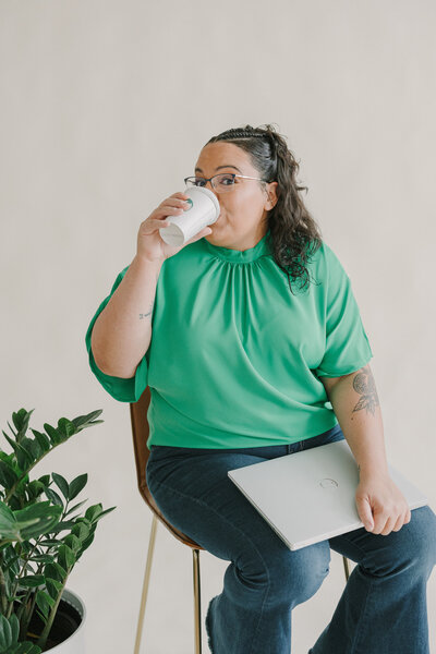 A person sitting in a chair drinking a cup of coffee
