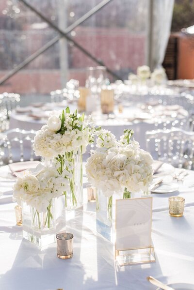 Reception table setting with white flowers in glass vases