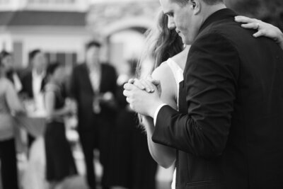 Bride and Groom hug and laugh surrounded by their bridal party. Bride has a flower crown and groom is in  a black tux. Anna Brace, a wedding photographer omaha nebraska