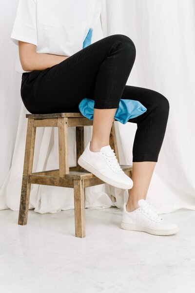woman sitting on stool wearing white sneakers