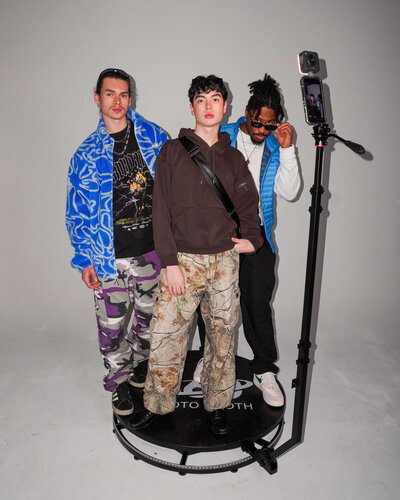 Three people pose on a 360-degree photo booth platform. Representing 660 Photo Pop's vendor profile for the Crush Collective wedding show.