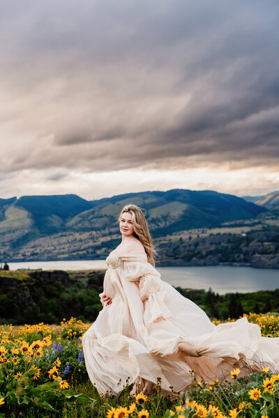 a beautiful pregnant mama in front of a cliff surrounded by beautiful wildflowers