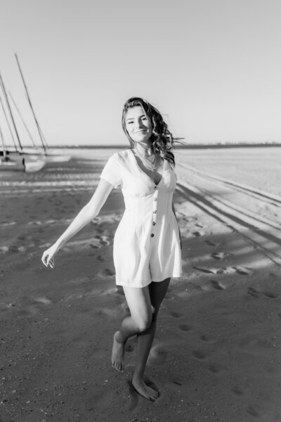 Black and white image of a teen girl dancing on the beach in Ocean City, New Jersey. She is wearing a white romper.