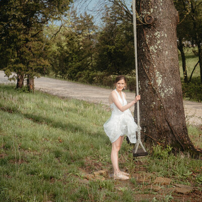 Bride in short dress enjoys a swing in the countryside