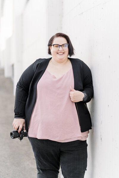 a lgbtq sacramento wedding photographer poses with her camera for her branding photos