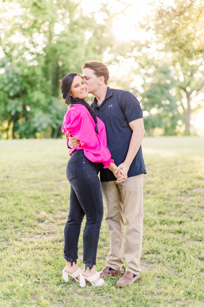 Happy couple in casual outfits pose for engagement photos in wildflower field in Madison, MS.