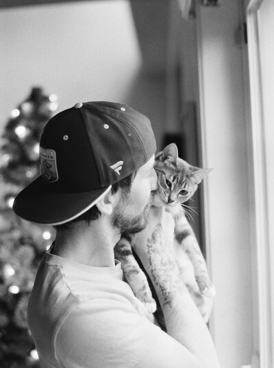 Seattle Wedding Photographer Joe Carvalho cuddles with his kitten peanutbutter in black and white film image 