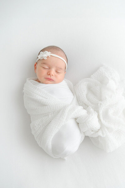 Newborn baby girl wrapped in white during natural light session by Destin photographer Andrea Krey