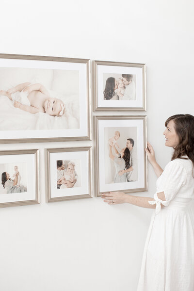 Woman hanging five frames on wall