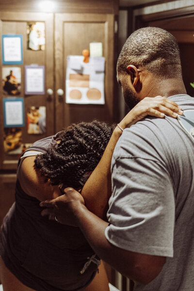 Tifton, GA birth photography:  wife leans on husband with her hands on his shoulders for support during a touch contraction