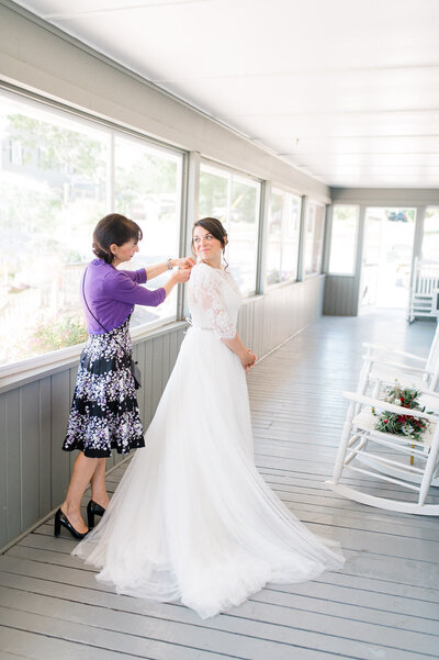 Mother-of-the-bride helps bride put on wedding dress
